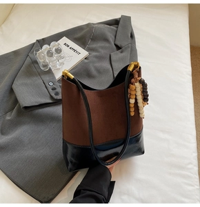 Détail du sac cabas bicolore en daim marron et base brillante noire avec perles