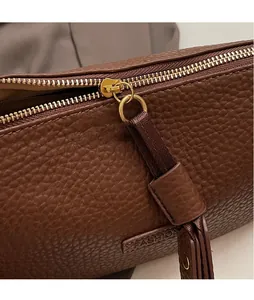 Détail du cuir grainé marron et de la fermeture éclair dorée avec tirette allongée robuste