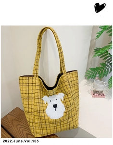 Detail of yellow plaid canvas tote bag with cute white puppy embroidery and textured fabric