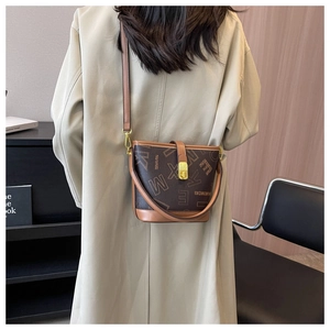 Détails du sac seau marron à monogramme avec finitions dorées porté par un mannequin