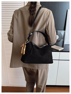 Retro black suede hobo shoulder bag with wooden bead charm in a minimalist setting