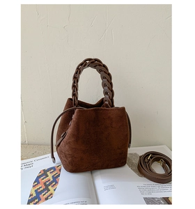 Detail of dark brown suede bucket bag with woven resin handle and drawstring closure
