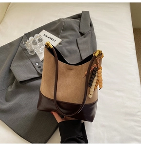Détails du sac cabas en daim kaki avec finitions en cuir marron et pompon en perles