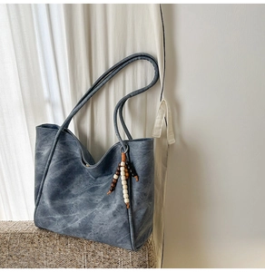 Detailed macro view of vintage blue leather tote bag with wooden bead fringe decor
