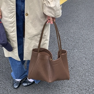 Vue détaillée du grand sac cabas tressé marron foncé porté par un mannequin