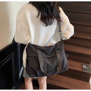 Detailed view of large black nylon tote bag with adjustable shoulder straps and zipper pocket