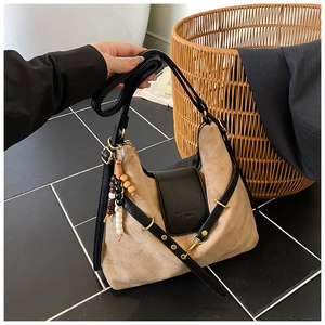 Détail du sac beige en daim avec bandoulière en cuir noir et pendentif à perles colorées