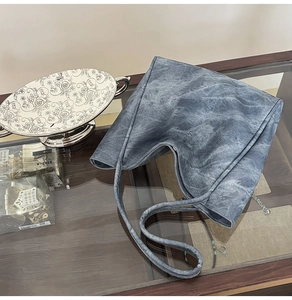 Top view of grey-blue tote bag with washed texture and shoulder strap on glass