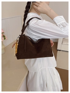 Detail of dark brown suede shoulder bag with bohemian wood bead charms and zipper closure