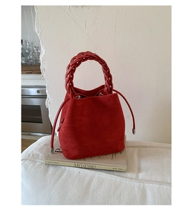 Detail of red suede bucket bag featuring a thick woven handle and drawstring closure