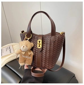 Dettaglio della borsa a secchiello intrecciata marrone scuro con chiusura dorata e orsetto