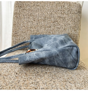 Detail view of denim tote bag featuring dark wooden bead accents on the handle