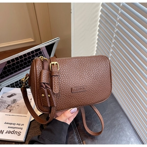 Gros plan sur le cuir grainé marron et le gaufrage FASHION sur ce sac à bandoulière