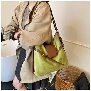Détail d'un sac dumpling en daim vert mat avec bandoulière en cuir et pendentif perlé