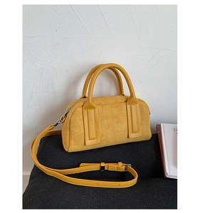 Macro shot of yellow suede Boston bag featuring leather handles and silver hardware