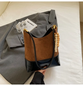Détail du sac fourre-tout en daim mat avec design color-block et breloque en perles
