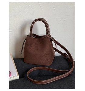 Close-up of dark brown suede bucket bag with wide woven handle and adjustable strap
