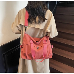 Detail view of pink large capacity canvas crossbody tote bag with wide strap on model