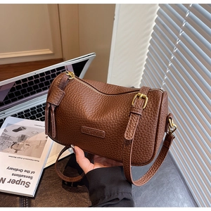 Gros plan sur le sac cylindre en cuir marron avec détails dorés et logo mode