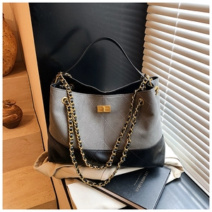 Détail du sac cabas en daim gris et cuir noir avec chaîne dorée et matelassage chic