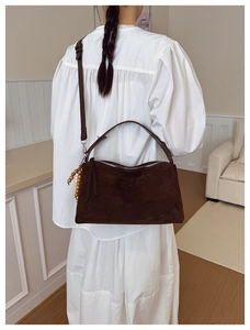 Detail of dark brown suede shoulder bag with ethnic beaded tassel and leather strap