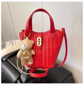 Dettaglio borsa a secchiello intrecciata rossa con chiusura dorata e ciondolo orso