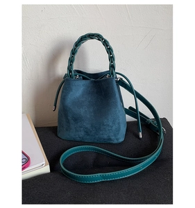 Detailed teal suede bucket bag featuring premium woven handle and adjustable strap