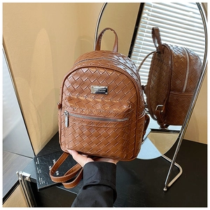 Dettaglio macro dello zaino in pelle PU intrecciata marrone con targhetta argentata