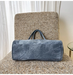 Detail view of reinforced stitching and durable base on blue denim tote bag for women