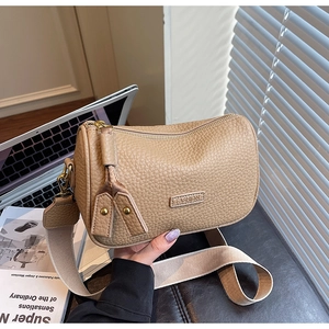 Détails du sac en cuir grainé avec bandoulière large et finitions métalliques dorées