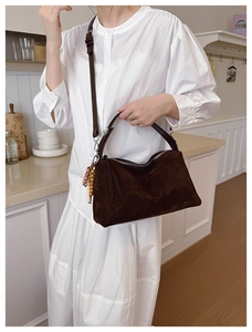 Detail of dark brown suede shoulder bag with retro wooden bead charm and long strap