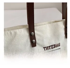 Dettaglio della borsa tote in velluto bianco con manici in pelle marrone e rivetti in metallo