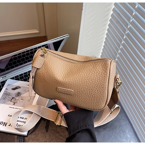Détail du sac tonneau en cuir kaki avec étiquette FASHION et bandoulière large