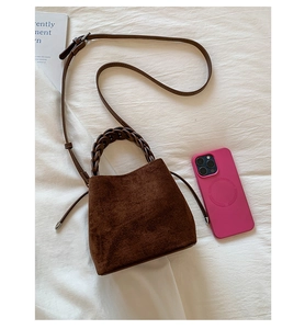 Detailed view of the dark brown suede bucket bag with woven handle and drawstring accents