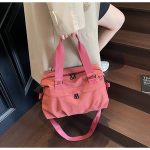 Coral pink large nylon travel tote with adjustable strap on wooden steps