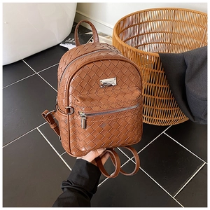 Dettaglio di un mini zaino in pelle intrecciata marrone con una targhetta logo in metallo