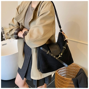 Détail du sac en toile noire avec rabat en cuir, œillets métalliques et perle en bois