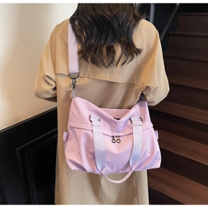 Detail of light purple canvas crossbody bag with double zippers worn over a camel coat