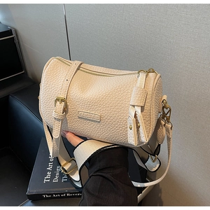 Détail du sac cylindrique crème avec logo FASHION et large bandoulière contrastée