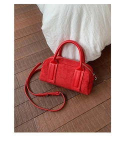 Macro shot of red suede bowling bag with smooth leather handles and metal zip detail