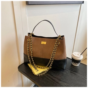 Détail des coutures en losange et du fermoir en métal sur le sac cabas en cuir marron