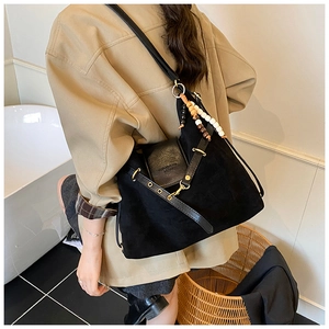Détail du sac dumpling en daim noir avec perles bohèmes et rabat en cuir sur modèle
