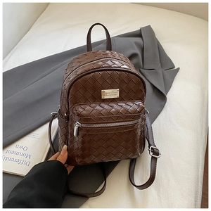 Dettaglio della trama in pelle intrecciata marrone scuro su uno zaino elegante e capiente