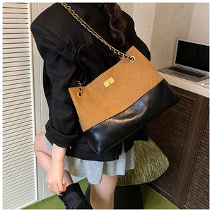 Détail d'un sac cabas bicolore en daim marron et cuir matelassé noir avec fermoir doré tournant