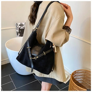 Détail du sac dumpling noir mat avec rabat en cuir et pompon décoratif en perles de bois