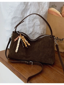 Retro dark brown suede shoulder bag with wooden beads on a rustic wooden table