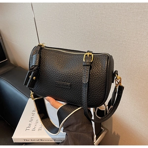Détail du sac bandoulière cylindrique noir avec large sangle et lettrage mode