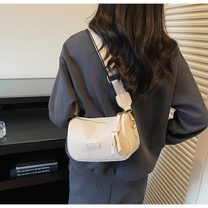 Détail d'un sac bandoulière beige en cuir grainé avec une large sangle à motifs