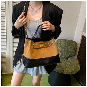 Detail of vintage quilted tote bag with brown suede and black leather patchwork chain strap