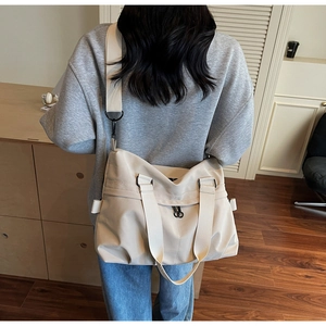 Rear view of model wearing cream canvas tote bag with wide strap in modern room